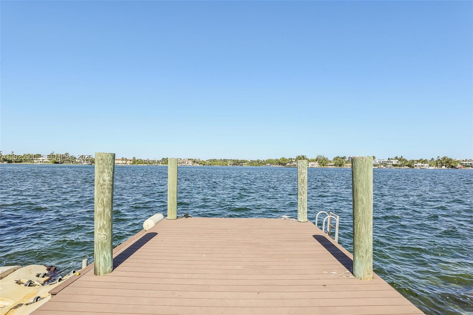 A wooden boat dock extends into a body of water under a clear blue sky — 1231 Stillwater Dr, Miami Beach FL 33141, MIAMI BEACH, FL
