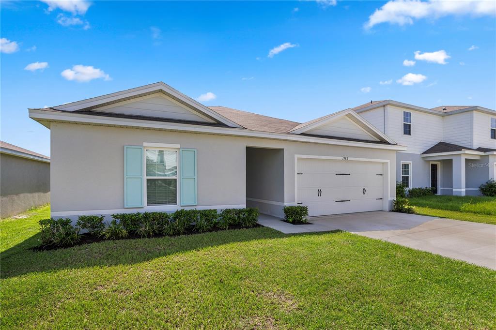 A single-story house with a light gray exterior, a two-car garage, and light blue shutters — 1582 FINNIGAN CIRCLE, HAINES CITY, FL