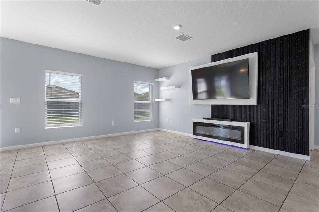 A living room features light blue walls, tile flooring, a wall-mounted television, and an electric fireplace — 1582 FINNIGAN CIRCLE, HAINES CITY, FL
