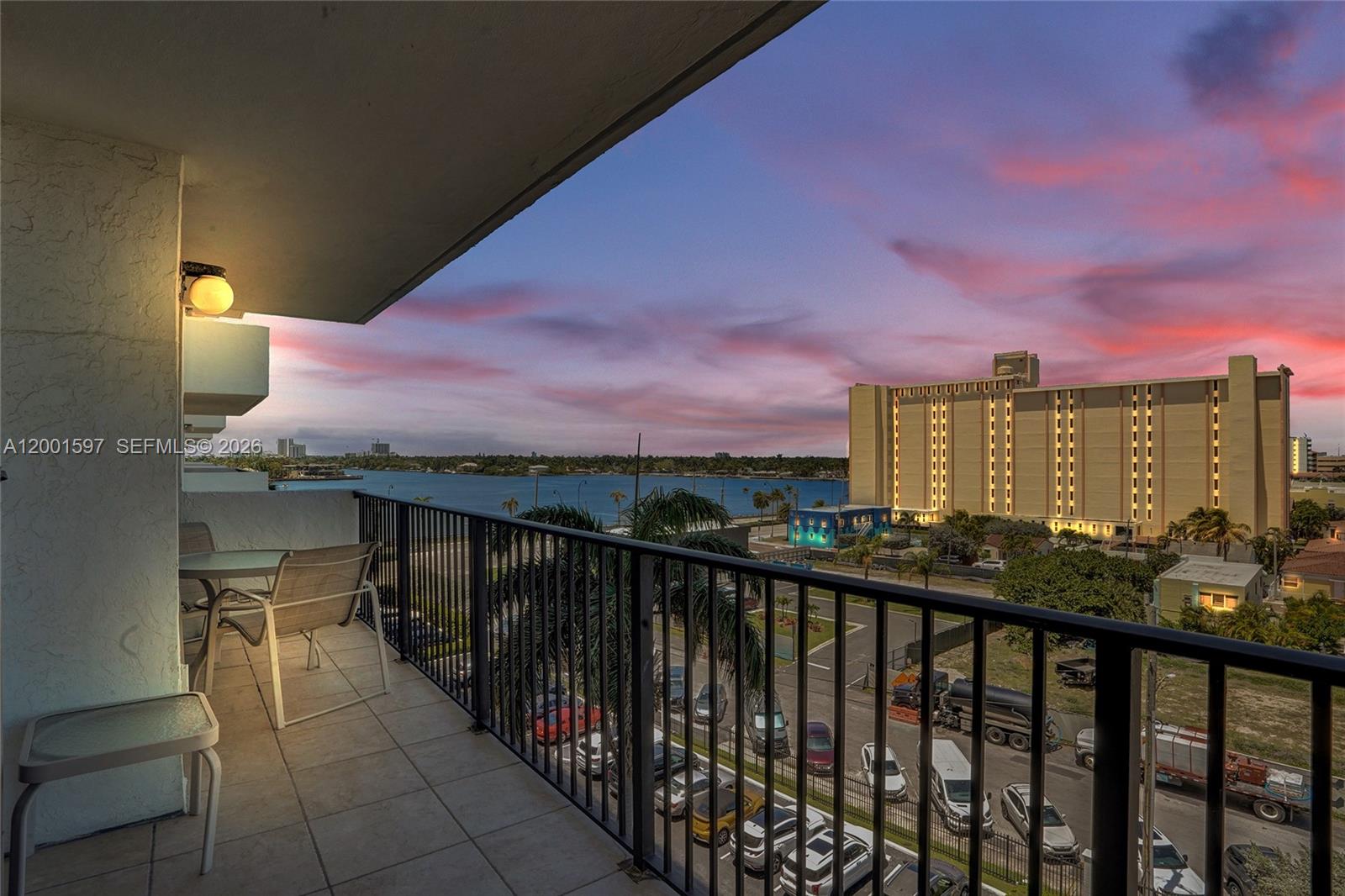 A balcony with patio furniture overlooks a parking lot, a body of water, and buildings — 1201 S Ocean Dr # 604N, Hollywood FL 33019, HOLLYWOOD, FL