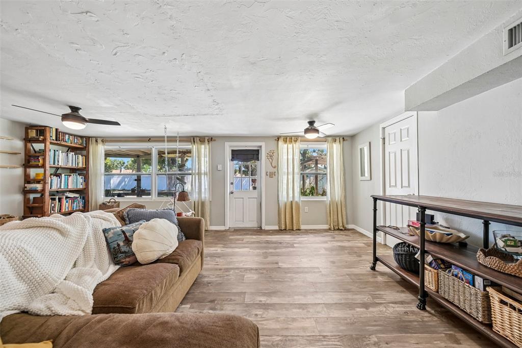 A living room features wood-look flooring, a brown sectional sofa, a bookshelf, and a door — 2818 11TH AVENUE W, BRADENTON, FL