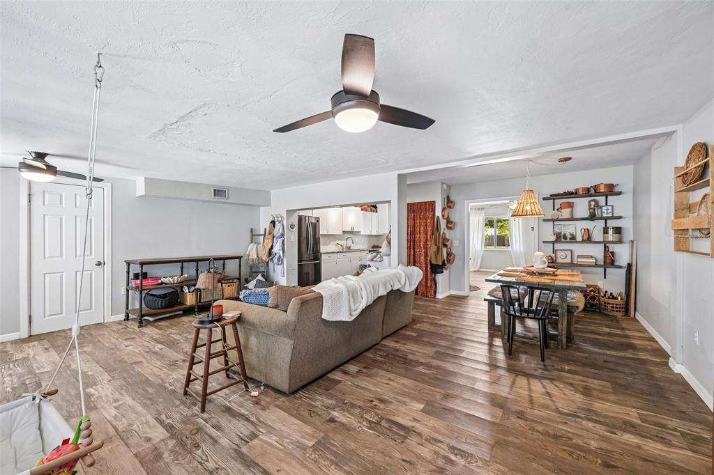 A living room and dining area with wood-look flooring, a ceiling fan, and open kitchen — 2818 11TH AVENUE W, BRADENTON, FL