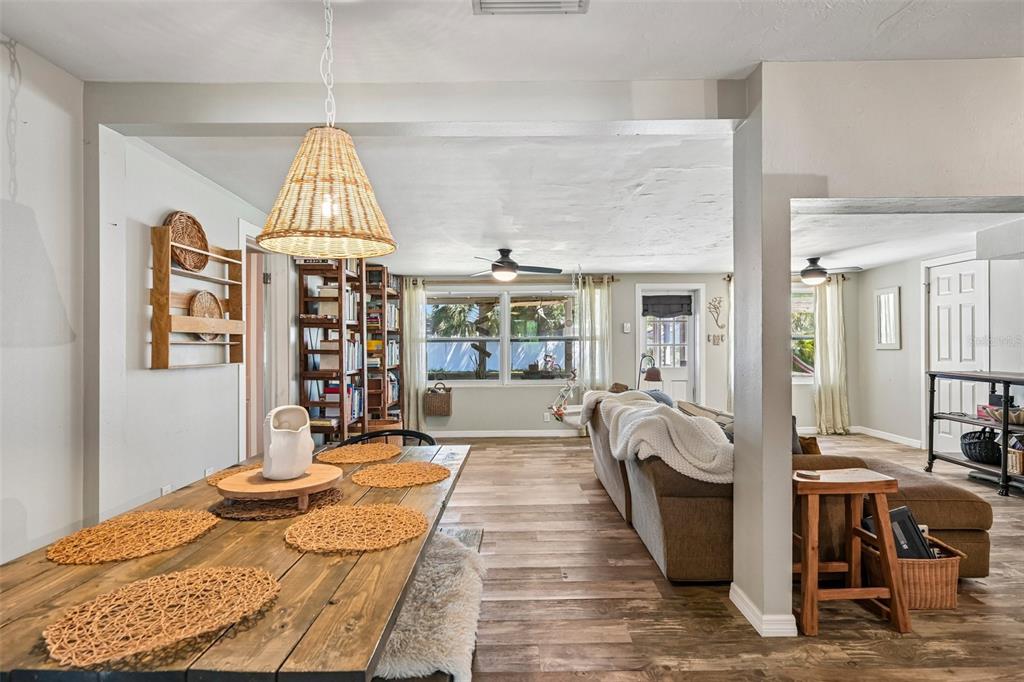 A dining area with a wooden table opens into a living room with wood flooring — 2818 11TH AVENUE W, BRADENTON, FL