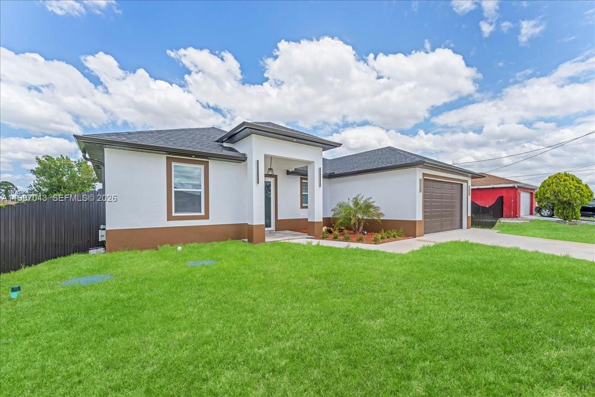 A single-story house with a white stucco exterior, brown trim, and a two-car garage — 2914 23rd st sw, Lehigh Acres FL 33976, LEHIGH ACRES, FL