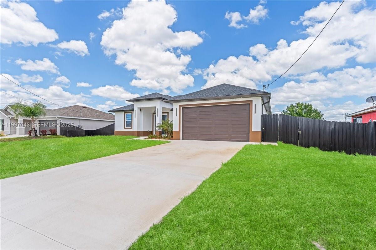 A single-story house with a brown garage door, white stucco exterior, and a green lawn — 2914 23rd st sw, Lehigh Acres FL 33976, LEHIGH ACRES, FL