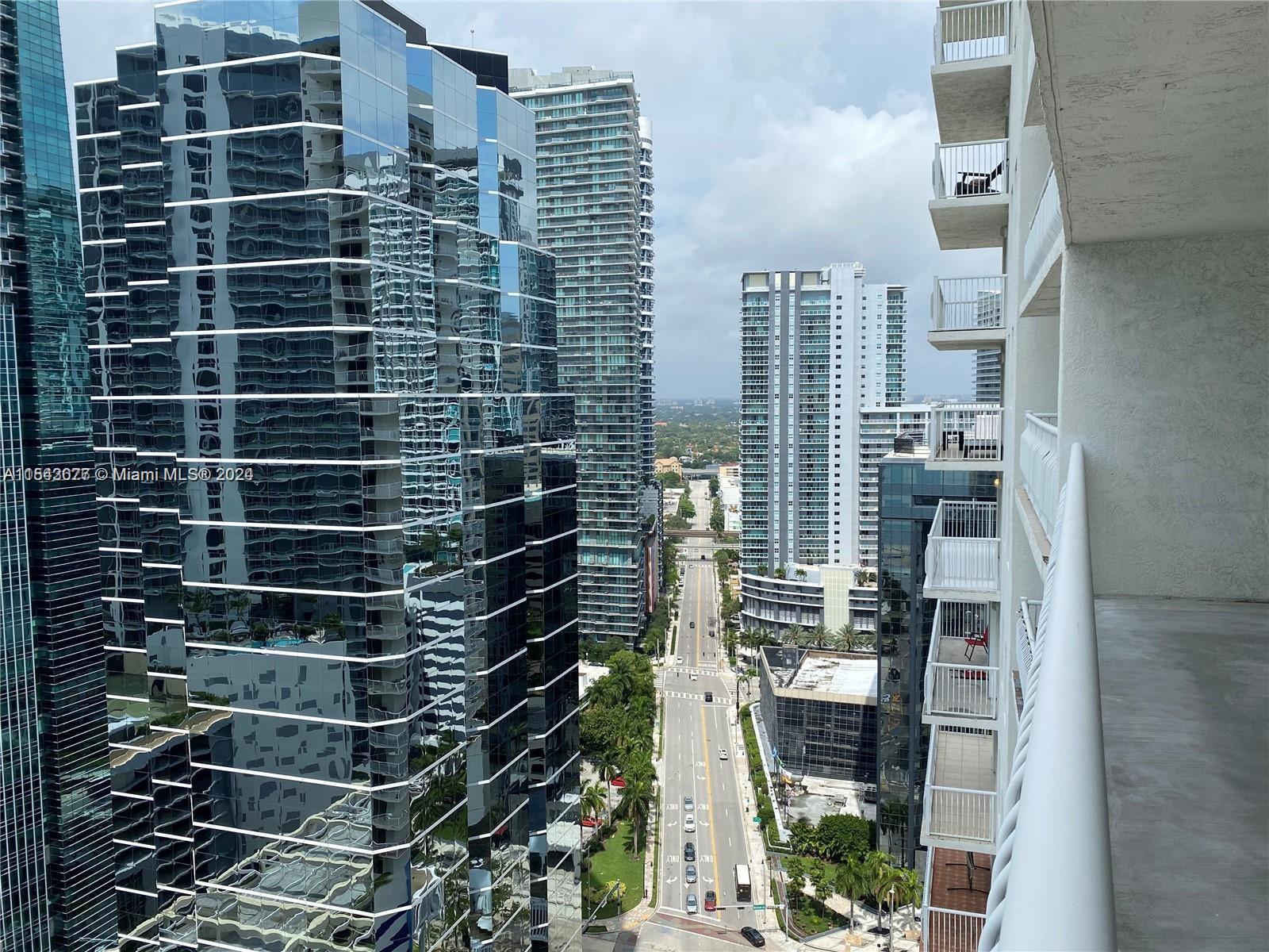 A high-angle view from a balcony overlooks a city street lined with tall glass skyscrapers — 1200 Brickell Bay Dr # 3119, Miami FL 33131, MIAMI, FL