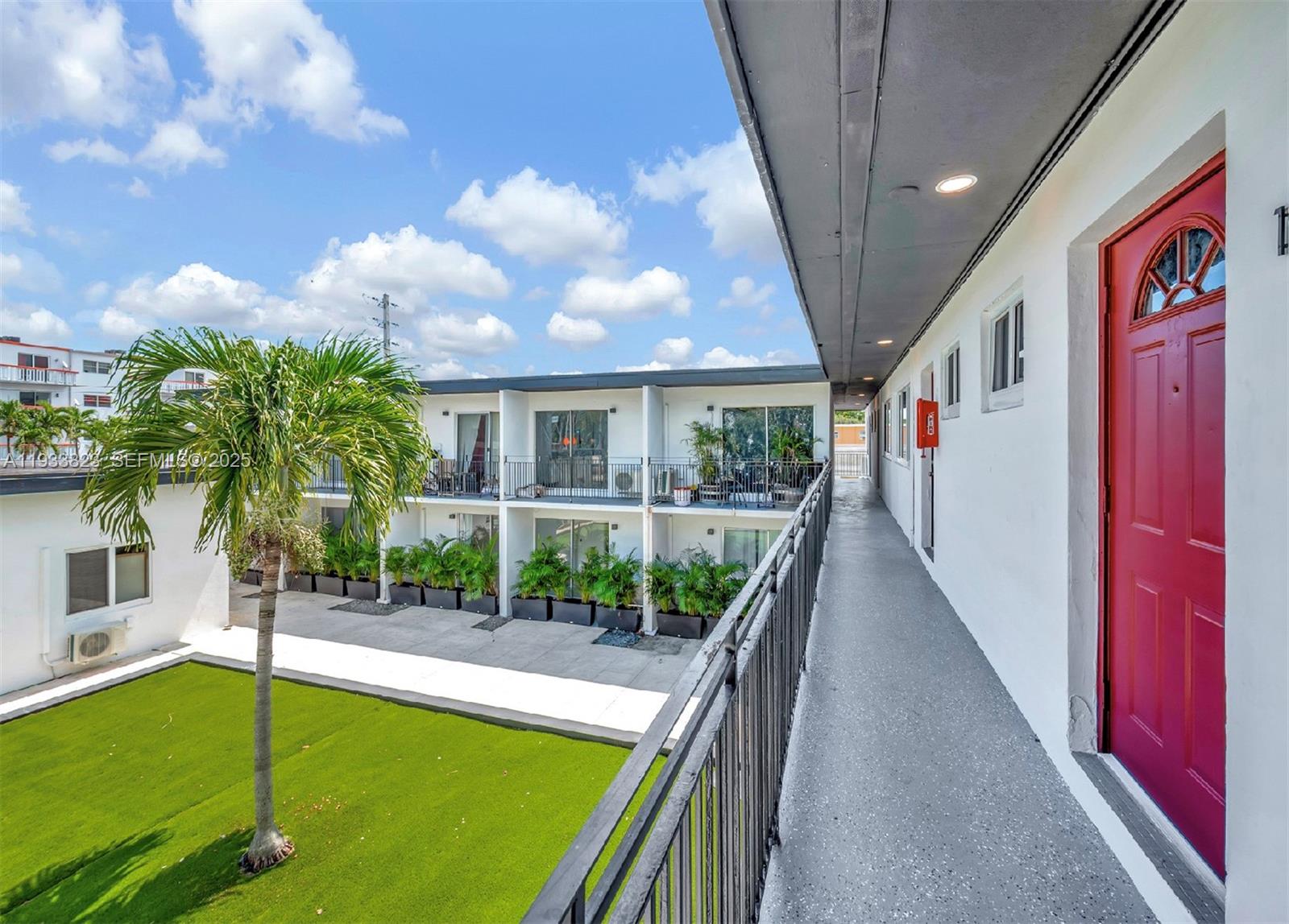 An exterior walkway overlooks a courtyard with a palm tree and a green lawn — 14280 NE 6th Ave, North Miami FL 33161, NORTH MIAMI, FL