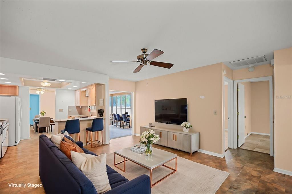 A living room with a ceiling fan, television, and an adjacent kitchen with bar seating — 1112 40TH AVE NE, ST PETERSBURG, FL