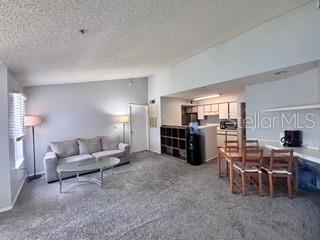 A living room with gray carpet, a sofa, and an adjacent dining area with a kitchen — 2212 GRAND CAYMAN COURT UNIT 1637, KISSIMMEE, FL