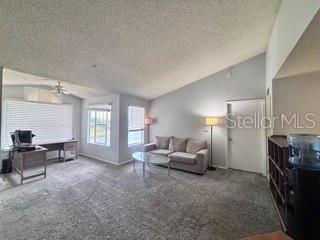 A living room with a vaulted ceiling, gray carpet, a desk, and a sofa — 2212 GRAND CAYMAN COURT UNIT 1637, KISSIMMEE, FL