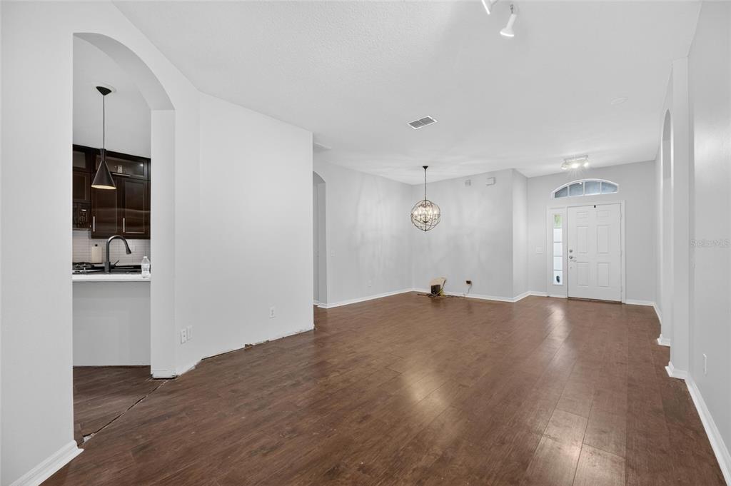 An open-concept living and dining area features dark wood flooring and white walls — 11901 NORTHUMBERLAND DRIVE, TAMPA, FL