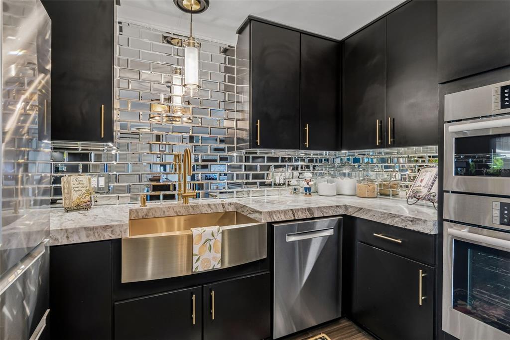 A kitchen features black cabinets, a rolling wooden island, and a mirrored tile backsplash — 5200 BRITTANY DRIVE S UNIT 1508, ST PETERSBURG, FL