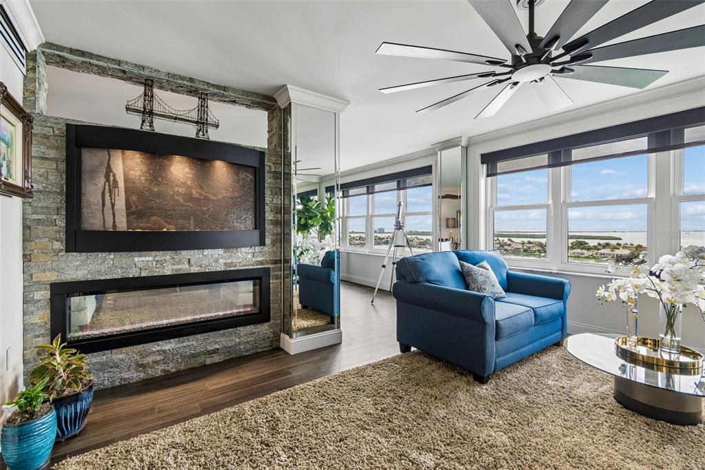 A living room features a grand piano, a fireplace with a television, and large windows — 5200 BRITTANY DRIVE S UNIT 1508, ST PETERSBURG, FL