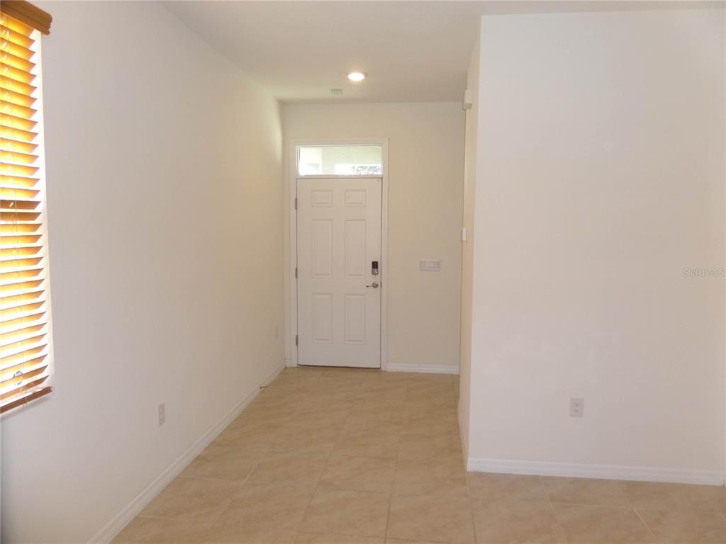 An entryway with a white front door, tile flooring, and a window with wooden blinds — 8051 PENROSE PLACE, WILDWOOD, FL