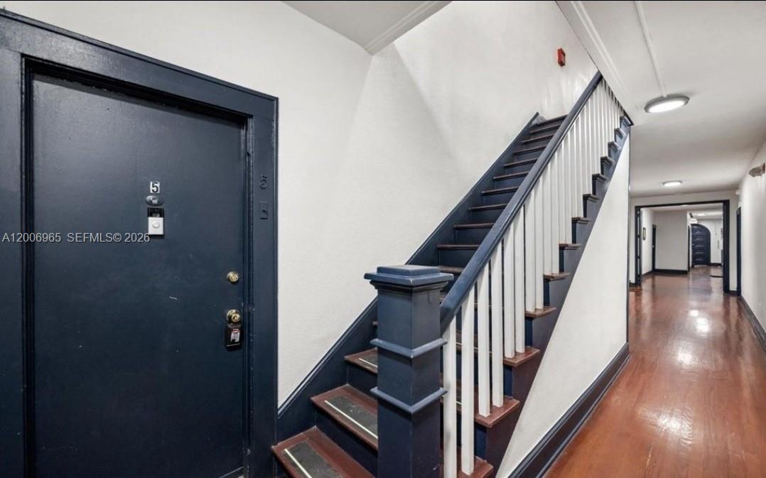 A dark blue door labeled 5 sits next to a wooden staircase in a hallway — CORAL GABLES, FL