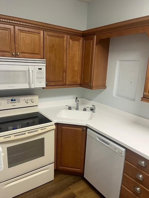 A kitchen features wooden cabinets, white countertops, a white stove, and a white dishwasher — CORAL GABLES, FL