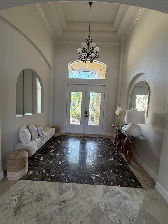 An entryway features a high tray ceiling, a chandelier, dark marble flooring, and arched wall niches — 1837 WATERMERE LANE, WINDERMERE, FL