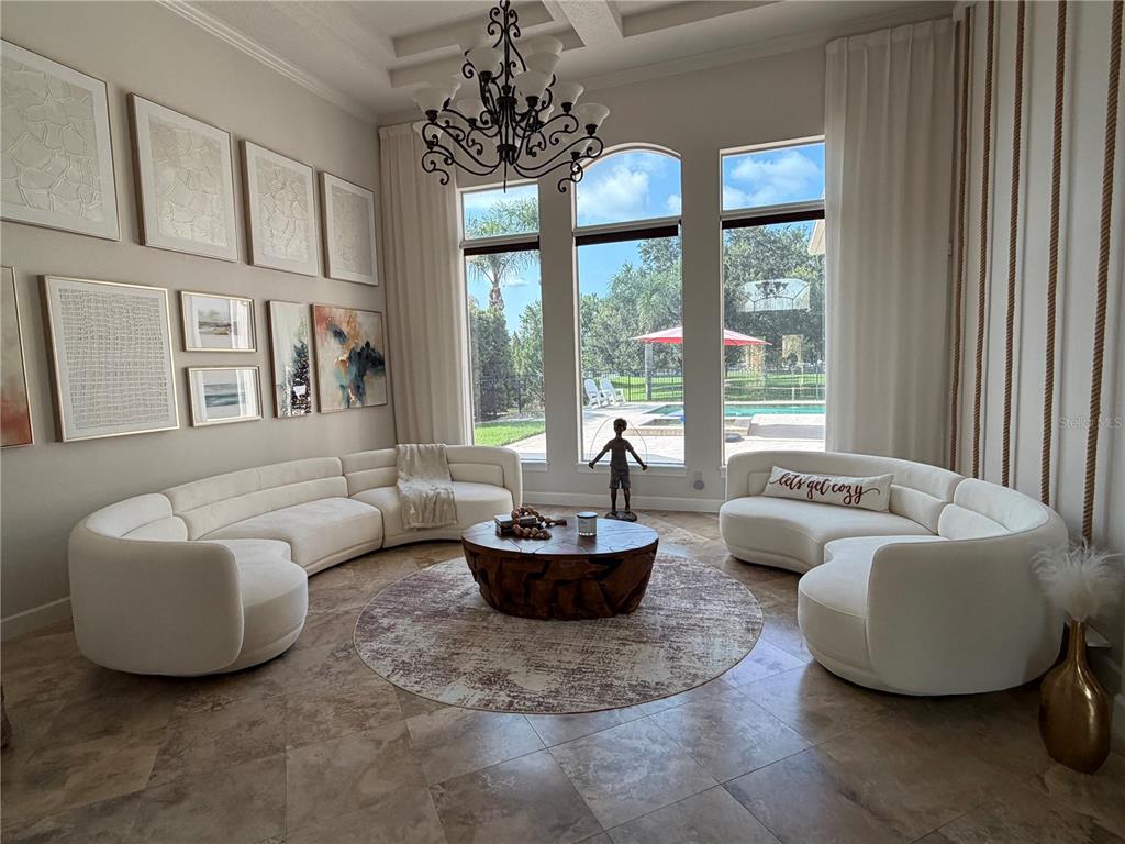 A living room features curved white sofas, a wooden coffee table, and large arched windows — 1837 WATERMERE LANE, WINDERMERE, FL