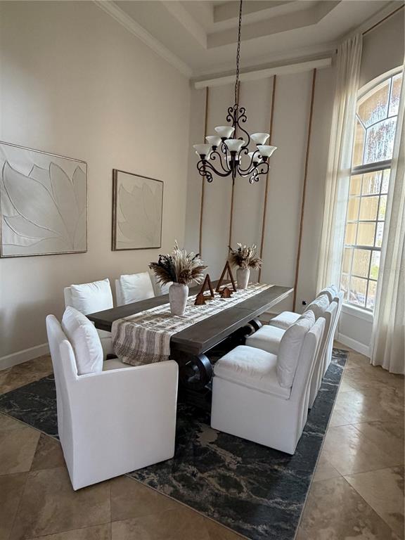A formal dining room features a dark wood table, white upholstered chairs, and a chandelier — 1837 WATERMERE LANE, WINDERMERE, FL