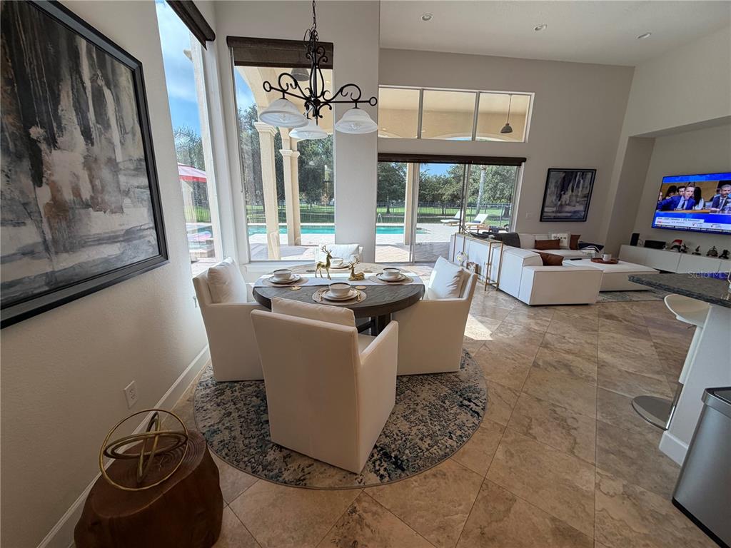 A dining area with a round table and white chairs sits before a pool view — 1837 WATERMERE LANE, WINDERMERE, FL