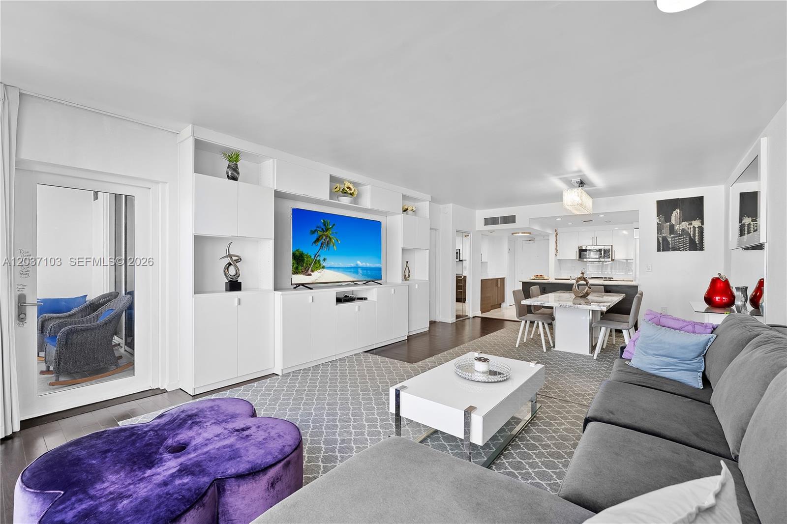 A living room features a white entertainment center, a grey sectional, and a purple ottoman — 10275 Collins Ave # 807, Bal Harbour FL 33154, BAL HARBOUR, FL