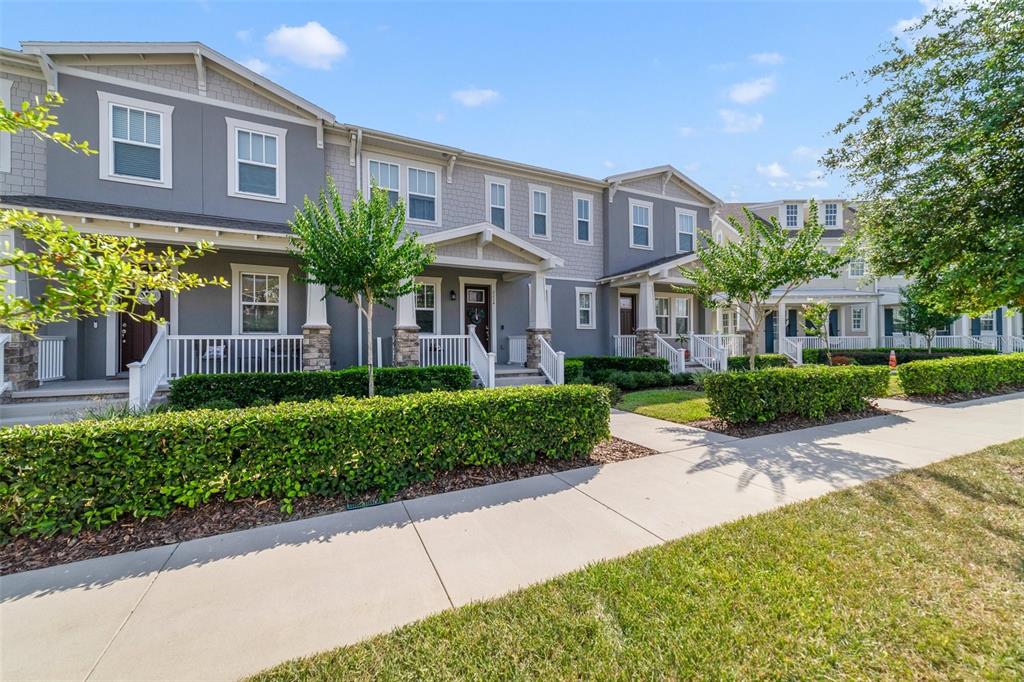 A row of gray townhouses with white trim, front porches, and manicured hedges along a sidewalk — 2224 CELEBRATION BOULEVARD, CELEBRATION, FL