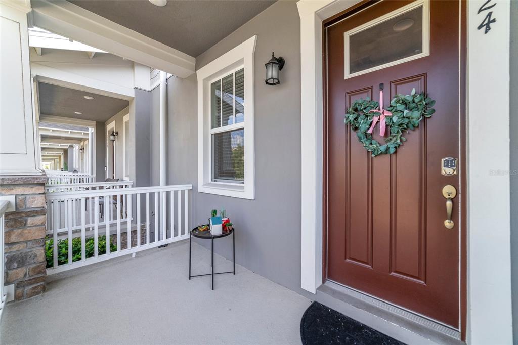 A covered front porch features a brown door with a heart-shaped wreath and white railing — 2224 CELEBRATION BOULEVARD, CELEBRATION, FL