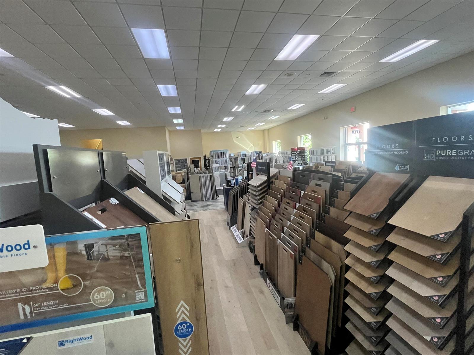A retail showroom displays numerous wood-look flooring samples on racks and shelves — 36070 Emerald Coast Parkway, FL 32541, FL