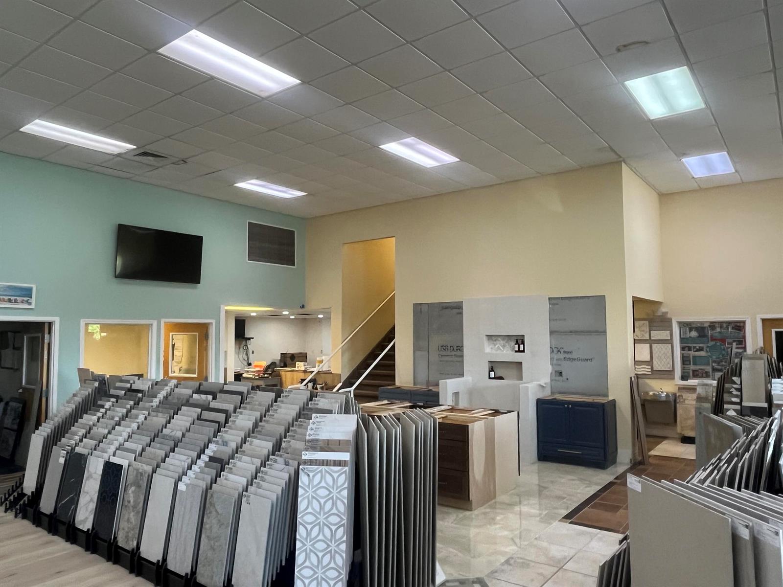 A showroom features rows of tile samples, a central display area, and a staircase — 36070 Emerald Coast Parkway, FL 32541, FL
