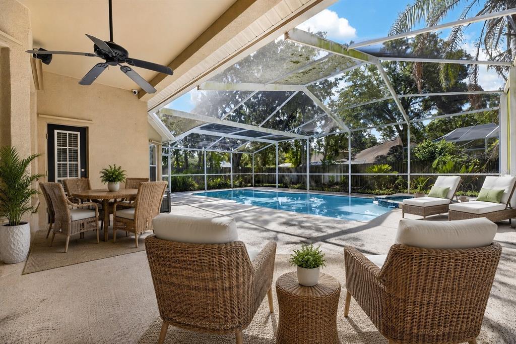 A covered patio with wicker furniture overlooks a screened-in swimming pool and backyard — 12519 RIVER BIRCH DRIVE, RIVERVIEW, FL