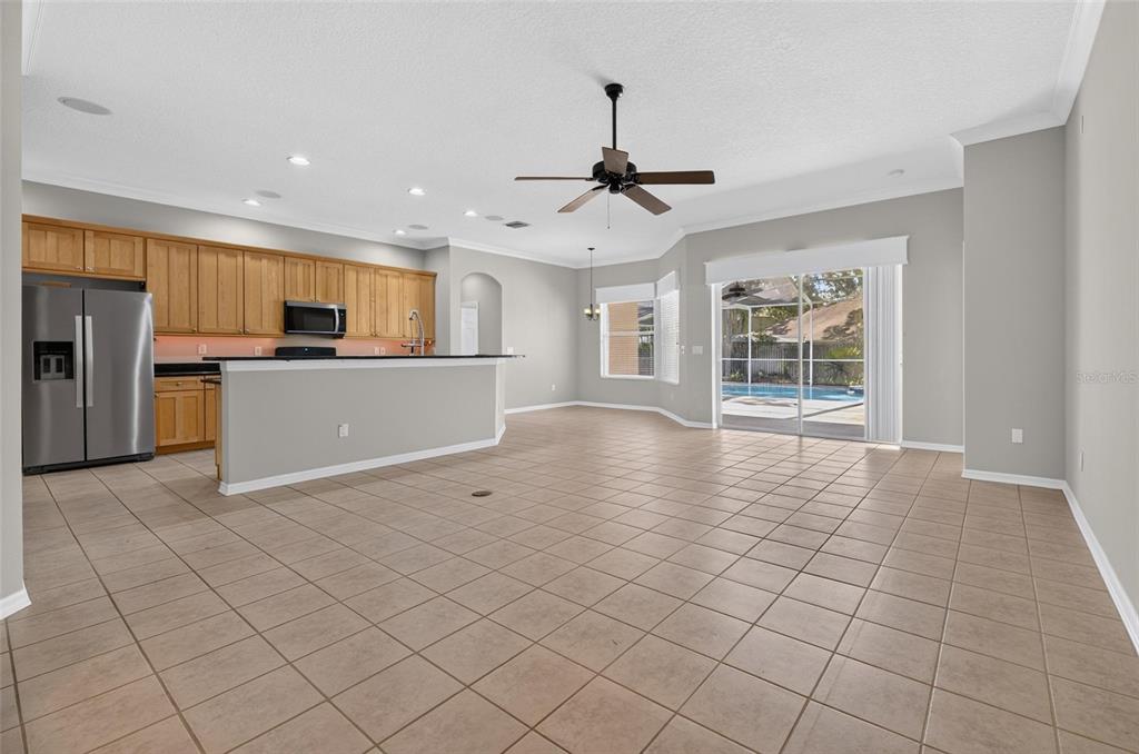 An open-concept kitchen and living area with tile flooring, light wood cabinets, and sliding doors — 12519 RIVER BIRCH DRIVE, RIVERVIEW, FL