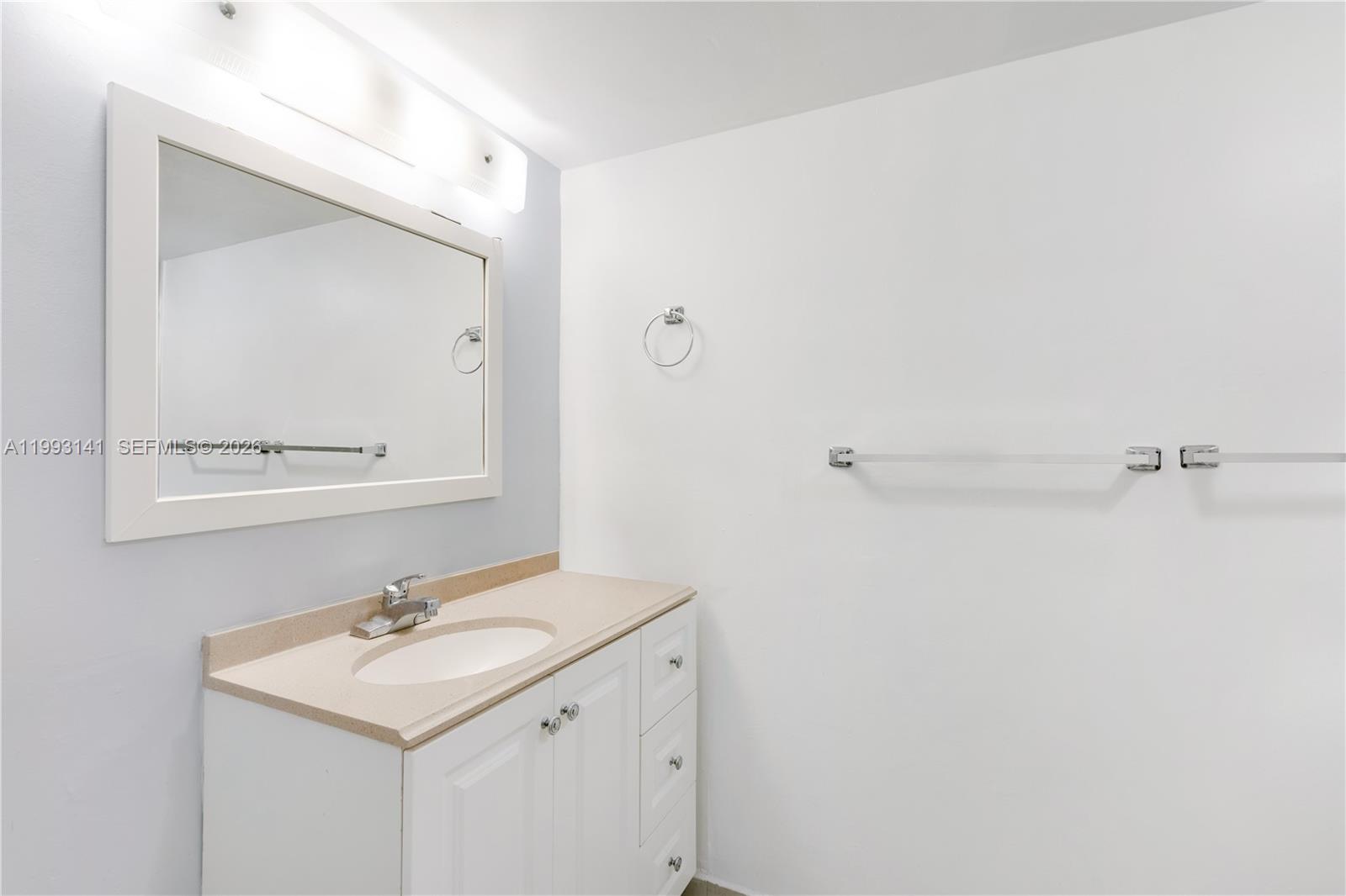 A bathroom features a white vanity with a beige countertop, a mirror, and towel racks — 9423 SW 76th St # W21, Miami FL 33173, MIAMI, FL