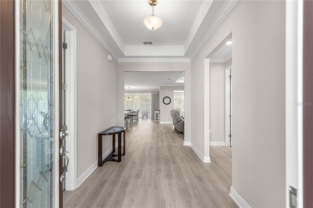 A bright foyer with light wood-look flooring leads into an open-concept living and dining area — 10050 SW 106TH CIRCLE, OCALA, FL