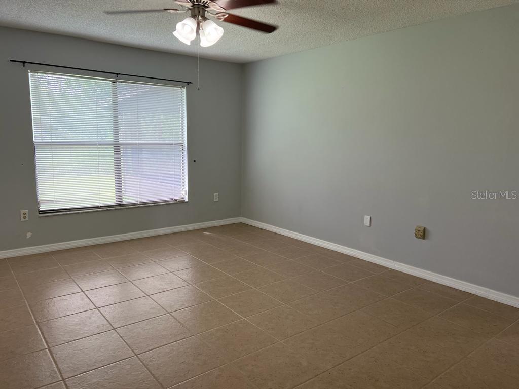 An empty room features light gray walls, tan tile flooring, and a ceiling fan — 116 TALAVERA LANE, KISSIMMEE, FL