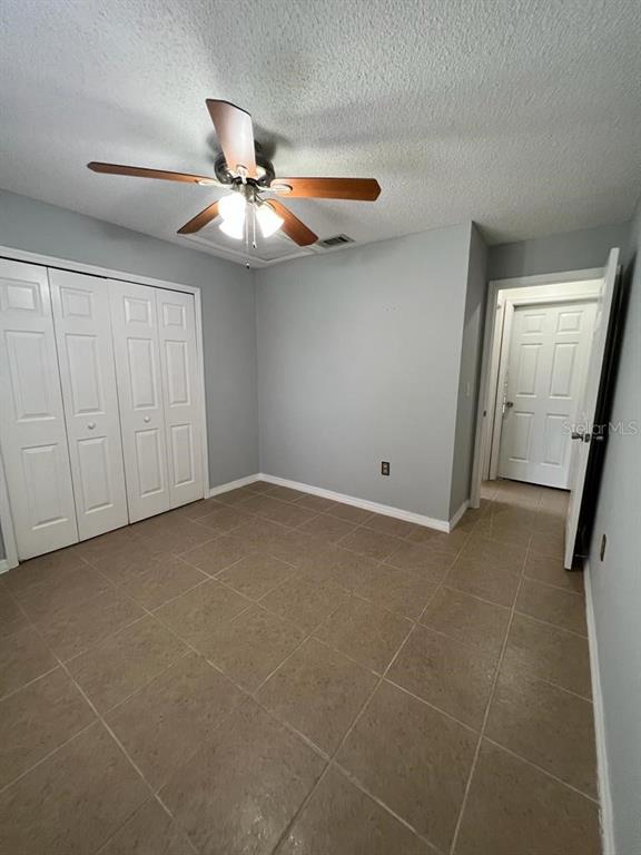 An empty bedroom features light gray walls, tile flooring, a ceiling fan, and white doors — 116 TALAVERA LANE, KISSIMMEE, FL