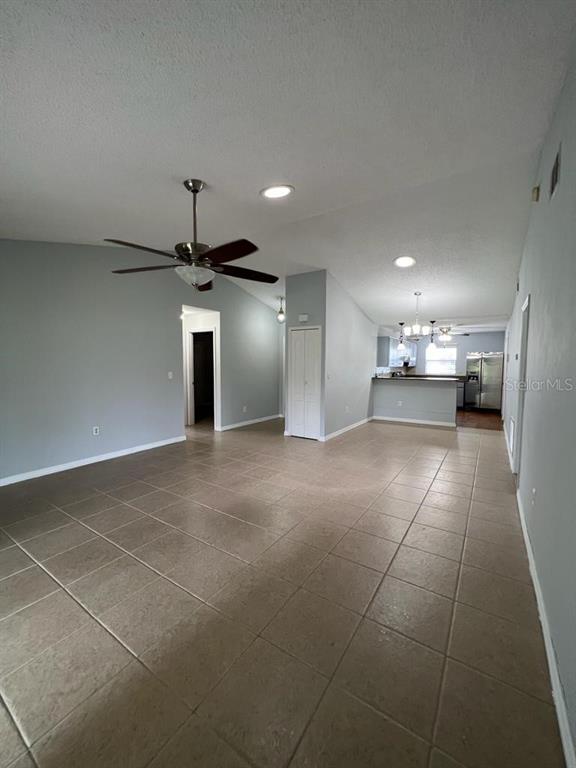 An open-concept living area features light gray walls, tile flooring, and a vaulted ceiling — 116 TALAVERA LANE, KISSIMMEE, FL