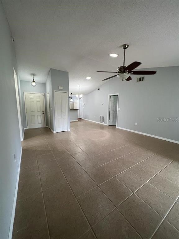 An open-concept living area features light-colored tile flooring, a vaulted ceiling, and a ceiling fan — 116 TALAVERA LANE, KISSIMMEE, FL