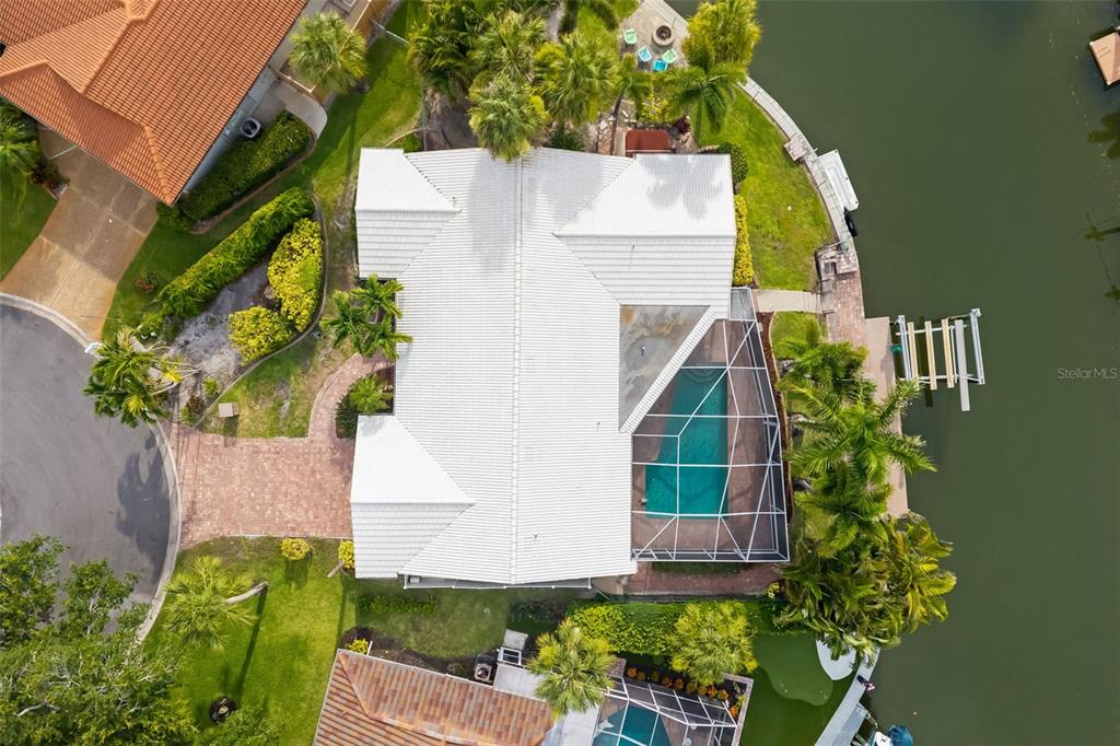 An aerial view shows a house with a white roof, a pool cage, and a dock — 565 COMMONWEALTH PLACE, SARASOTA, FL