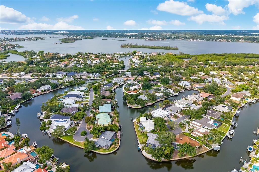 An aerial view shows waterfront homes on a canal with a circled property in center — 565 COMMONWEALTH PLACE, SARASOTA, FL