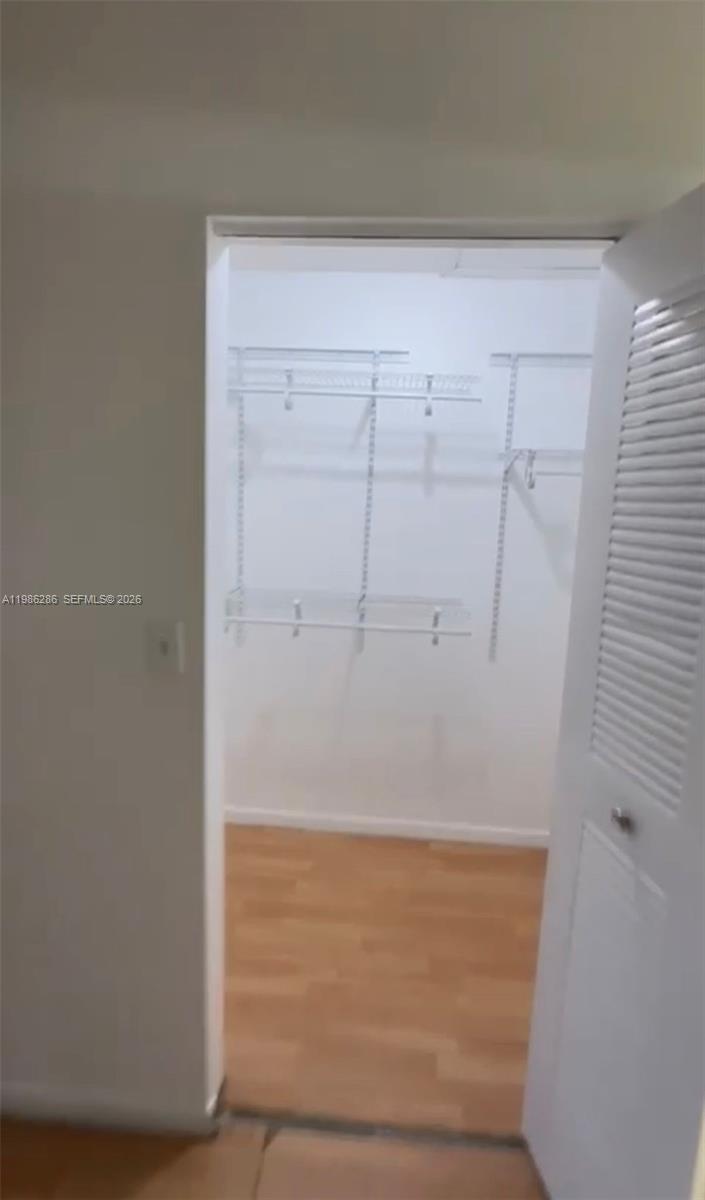 A walk-in closet features white wire shelving and light wood-look flooring — 15620 SW 80th St # 304, Kendall FL 33193, KENDALL, FL