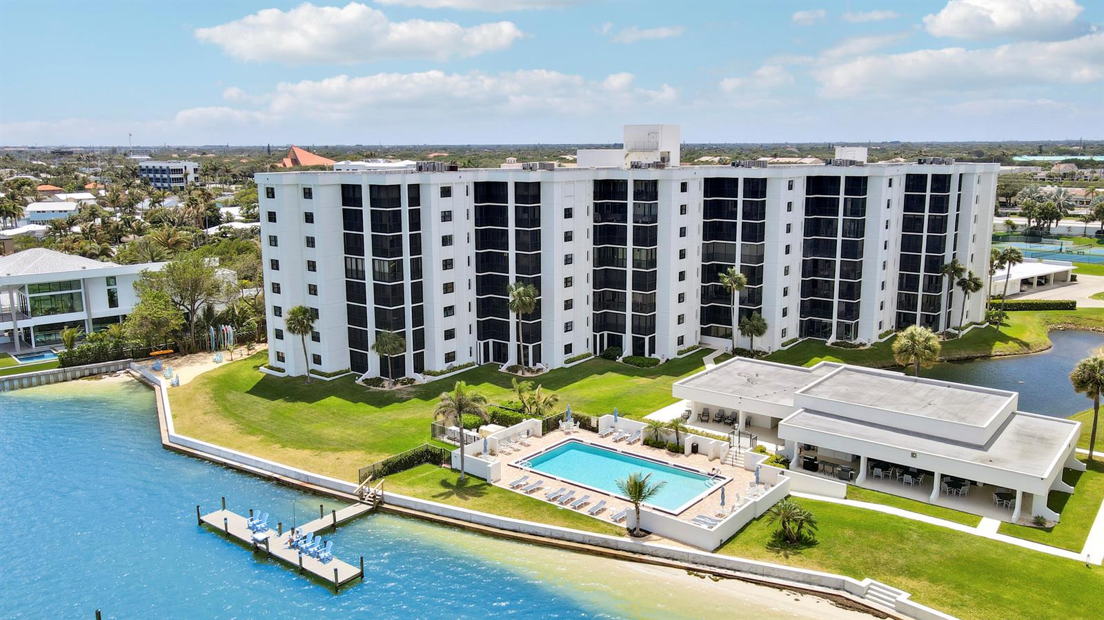 An aerial view of a white multi-story apartment building with a pool and dock — 19800 Sandpointe Bay Drive # 708, Tequesta FL 33469, TEQUESTA, FL