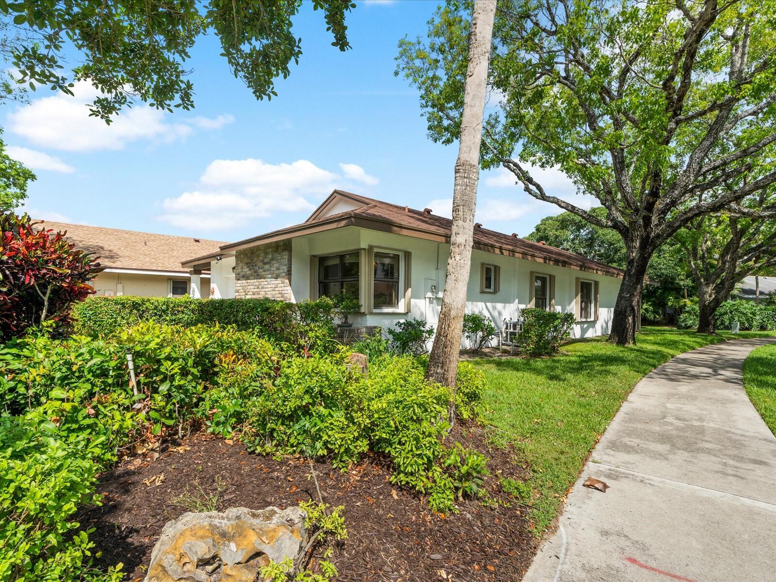 A single-story white house with a brown roof sits behind a landscaped yard and sidewalk — 2495 Dawn Tree Terrace, Coconut Creek FL 33063, COCONUT CREEK, FL