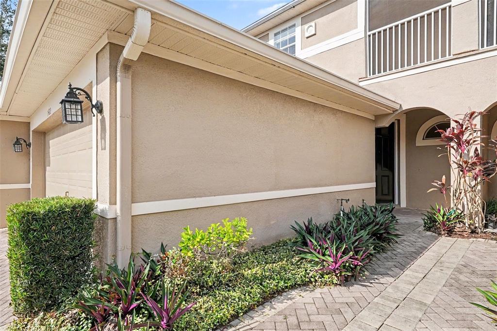 The exterior of a tan stucco house features a garage, a walkway, and landscaping — 7422 TERRACE RIVER DRIVE, TEMPLE TERRACE, FL