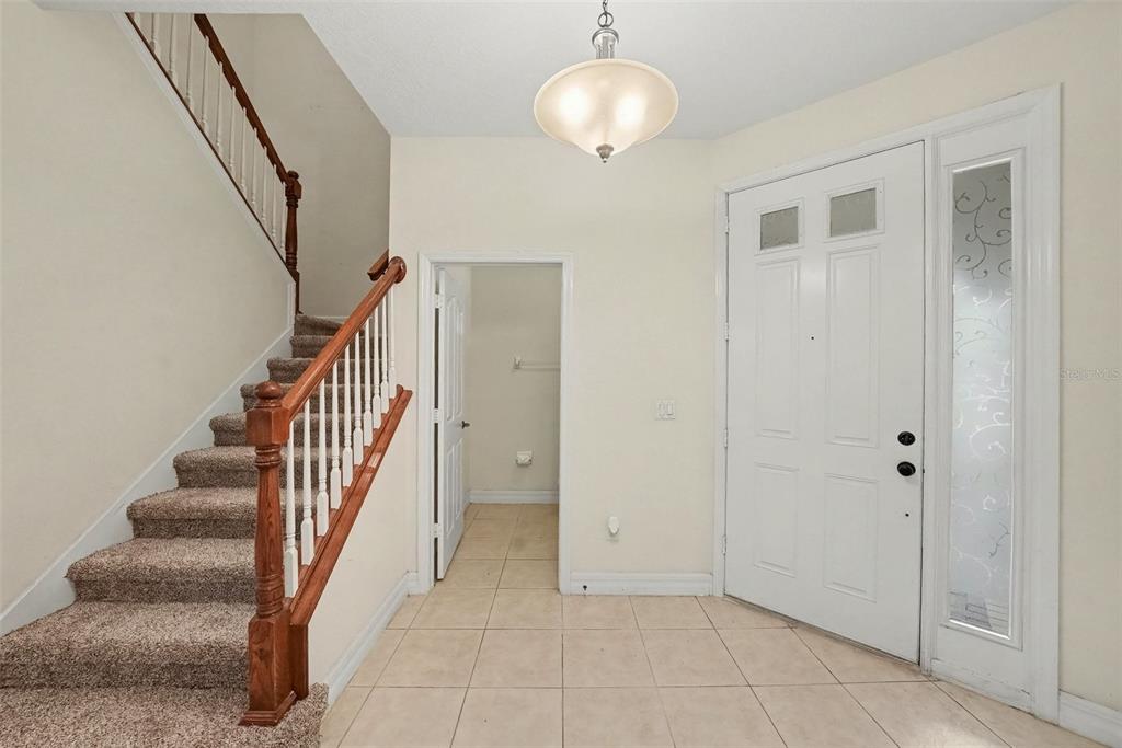 An entryway features a carpeted staircase, tile flooring, a white front door, and a light fixture — 7422 TERRACE RIVER DRIVE, TEMPLE TERRACE, FL