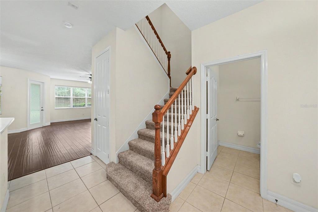 A carpeted staircase with a wooden railing sits between a tiled entryway and a living area — 7422 TERRACE RIVER DRIVE, TEMPLE TERRACE, FL