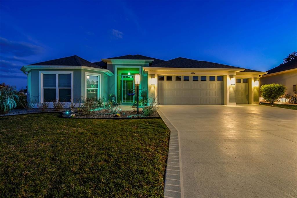 A single-story house with a garage and a concrete driveway at twilight — 1864 KEEL COURT UNIT 1, THE VILLAGES, FL