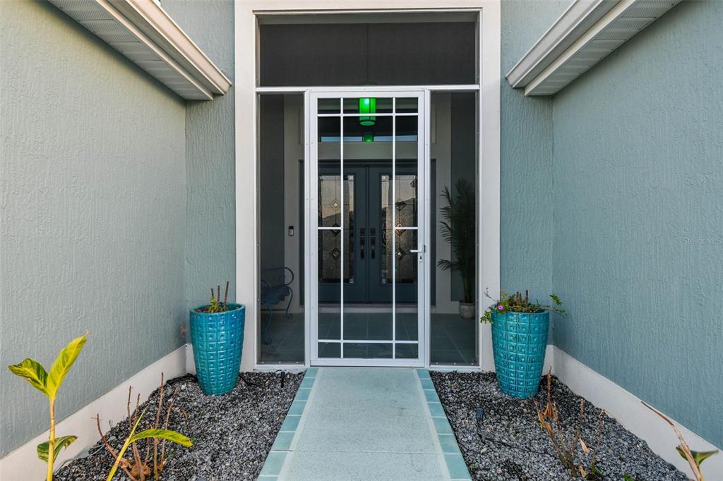 A front entryway features a white screen door, two blue planters, and a paved walkway — 1864 KEEL COURT UNIT 1, THE VILLAGES, FL