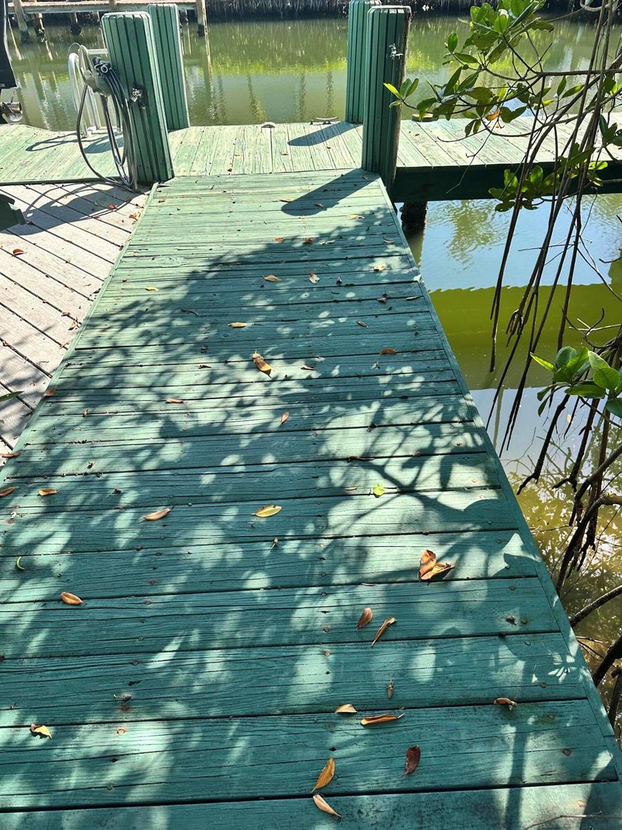 A green wooden dock extends over calm water, surrounded by mangrove roots and foliage — 1860 Cobia Drive, Vero Beach FL 32960, VERO BEACH, FL