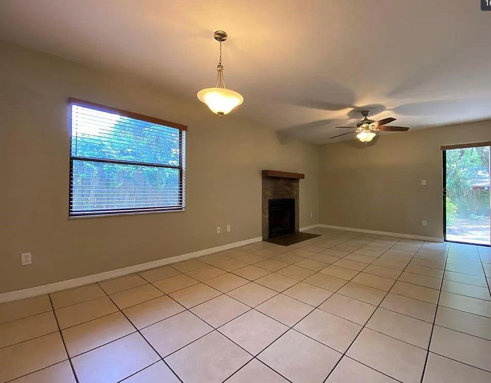 A living room features beige tile flooring, a fireplace, a ceiling fan, and sliding doors — 3254 HOWELL BRANCH ROAD, WINTER PARK, FL