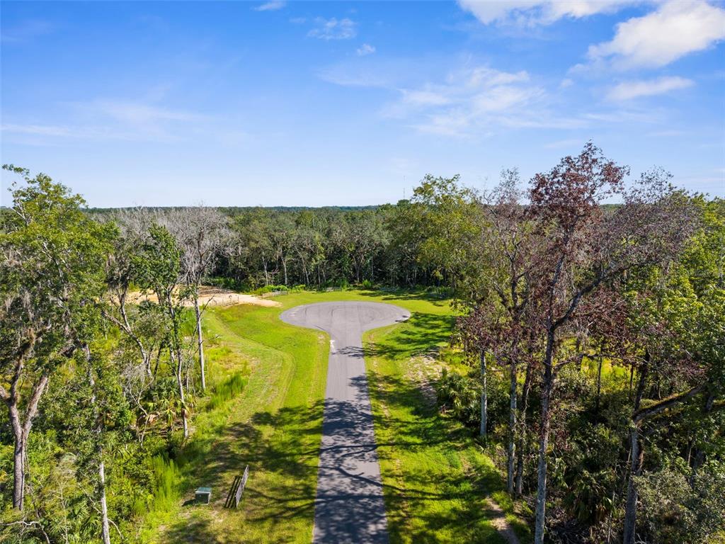 An aerial view shows a paved cul-de-sac surrounded by dense woods and green grass — REPUBLICAN (LOT 7) WAY, BROOKSVILLE, FL